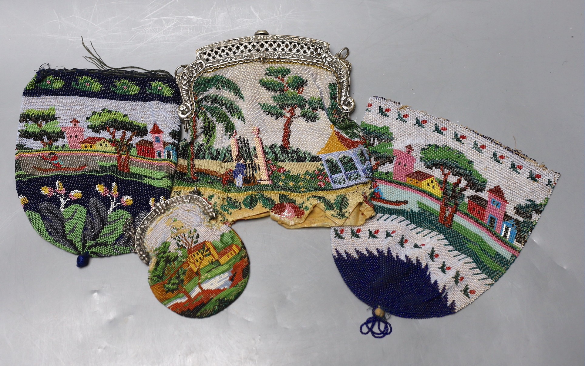 Three beaded bags/reticules, circa 1835-45 and a similar purse, all worked in multi coloured beads depicting tree lined landscapes with houses rivers and figures, possibly American, (4), framed bag 17 cms high
